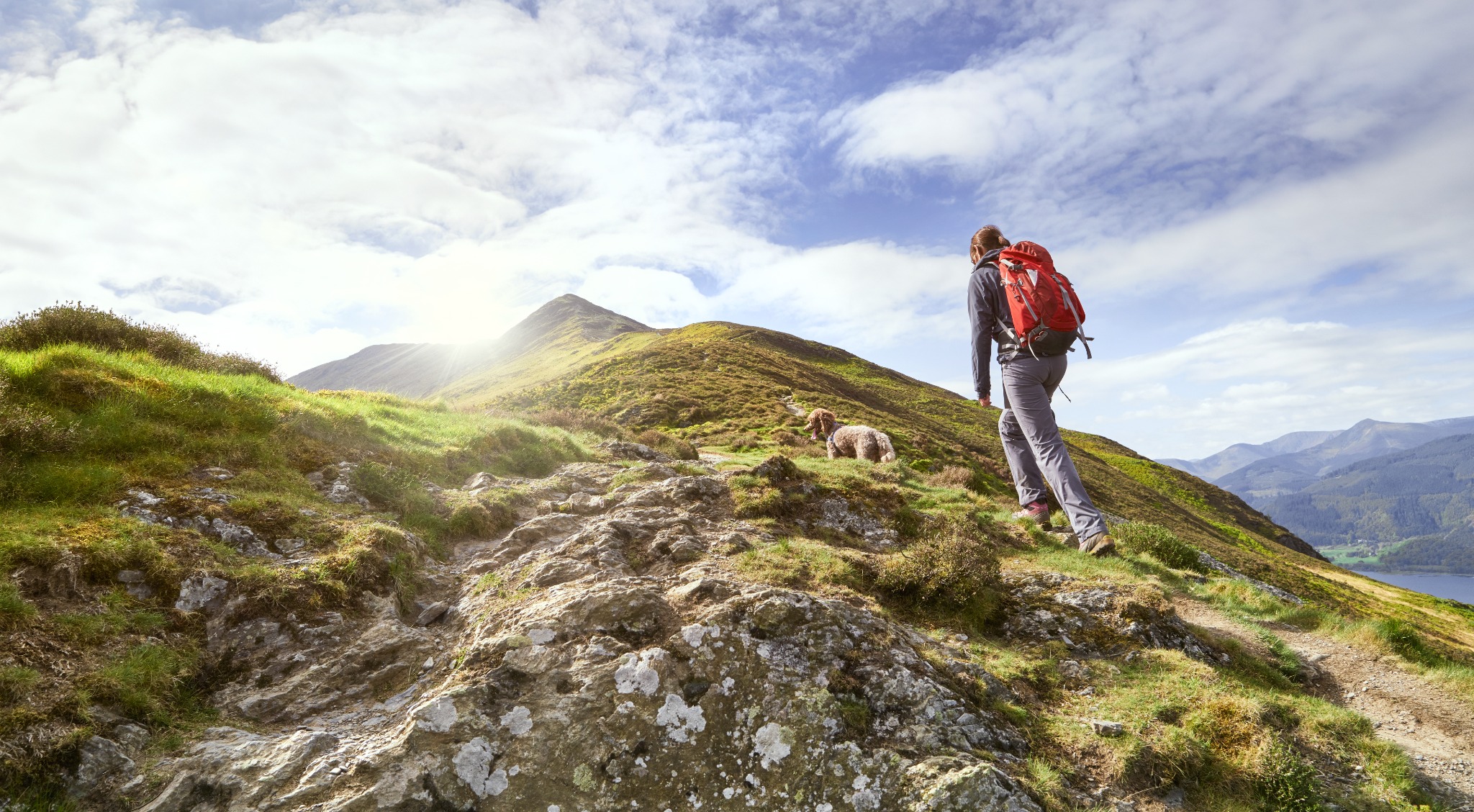 A hiker looking across the mountains and lakes of the Lake District